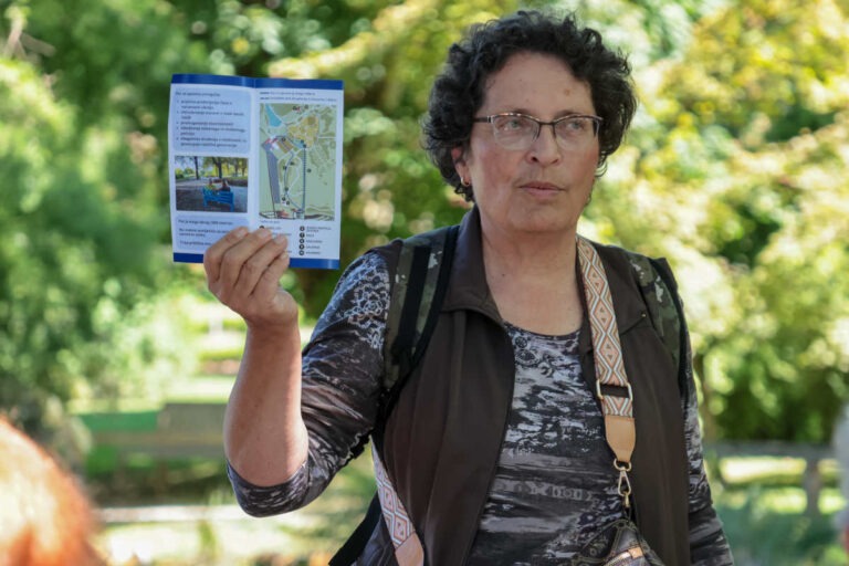 Sprehodi z Modro palico v Arboretumu Volčji Potok, dr. Zdenka Čebašek Travnik drži zloženko Poti za spomin z zemljevidom