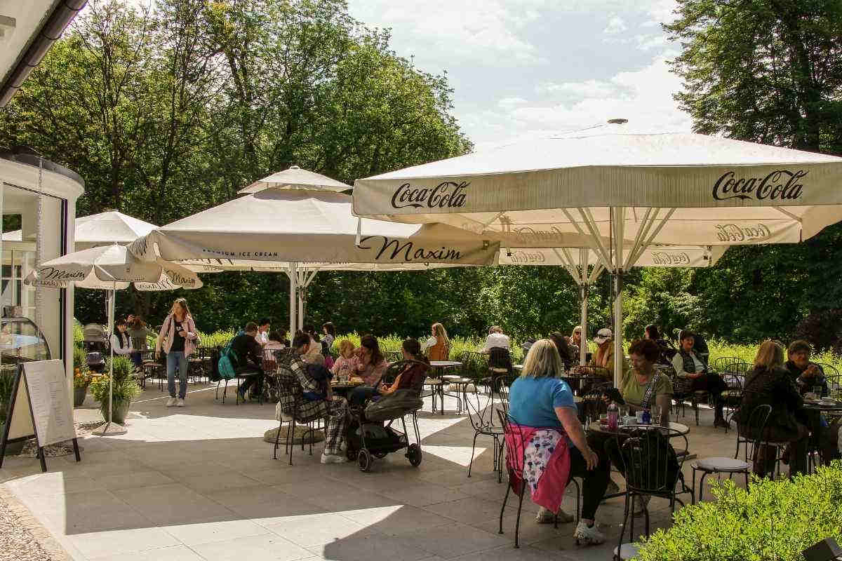 Terasa Kavarne Arboretum Terasa Kavarne Arboretum z obiskovalci v sončnem dnevu v Arboretumu Volčji Potok