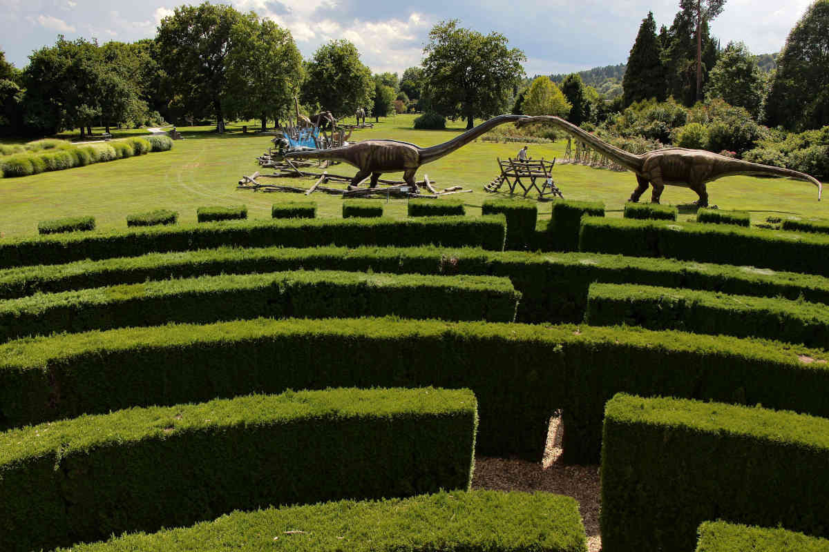 Labirint in dinozavri Labirint iz žive meje in dinozavri na travniku