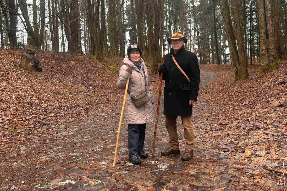 Zdenka in Ludvik na gozdni poti v Arboretumu Volčji Potok z lesenima palicama