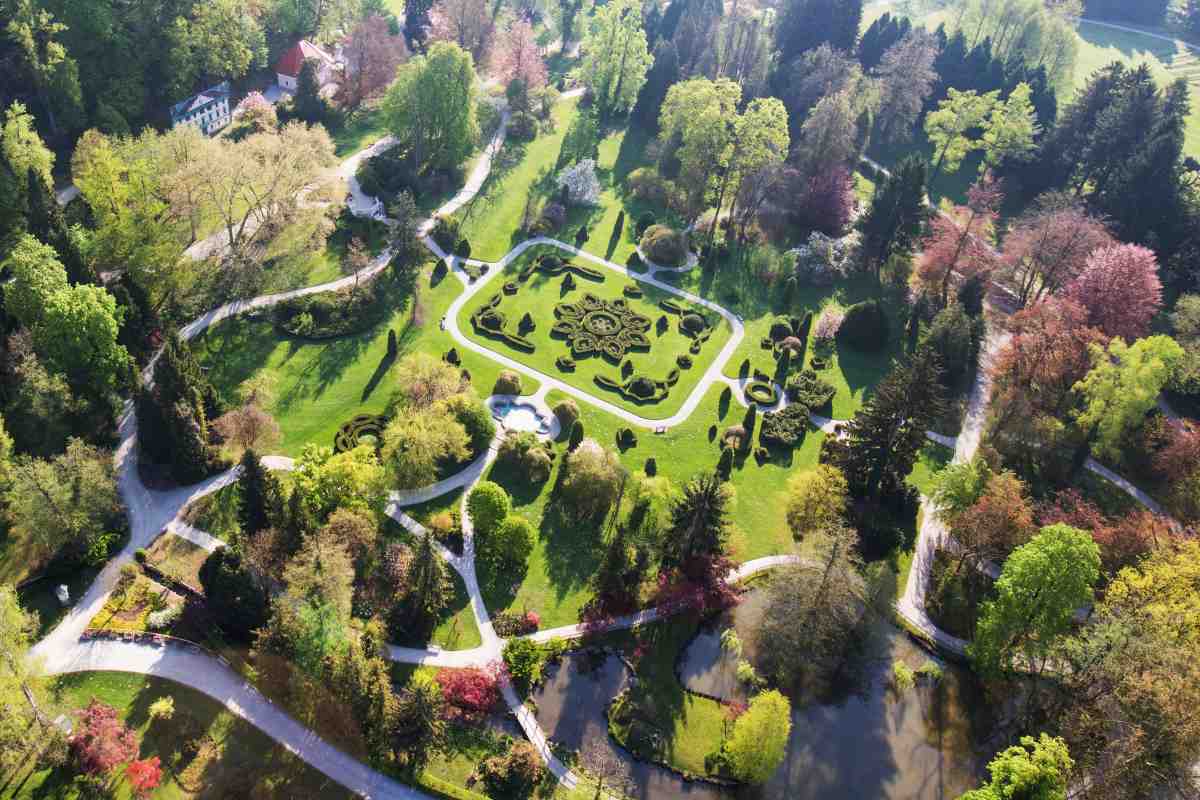 Arboretum-Volčji-Potok-Francoski-vrt Letalski posnetek Arboretuma Volčji Potok z geometrijsko oblikovanimi živimi mejami, vijugastimi pešpotmi in raznolikim drevjem.