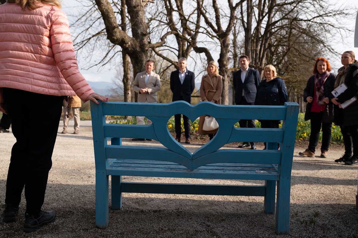 Modra klopca ljubezni in prijaznosti ob Poti za spomin Modra klopca z izrezom v obliki srca ob Poti za spomin v Arboretumu Volčji Potok, v ozadju županje, župani in člani Modre palice.