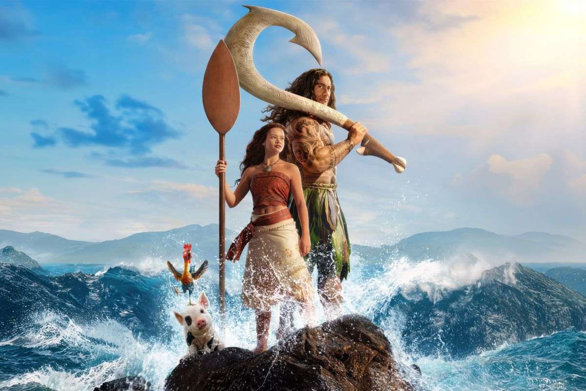 Vaiana in Maui stojita na skali med razburkanimi valovi, ob njiju sta pujsek in petelin, v ozadju pa se odpira svetlo nebo.
