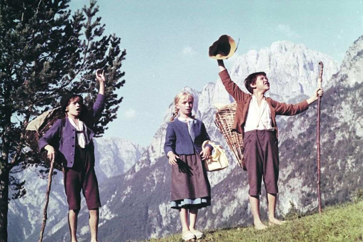 Prizor iz filma: deček in deklica stojita na gorskem travniku, v ozadju pa se dvigajo visoke gore.