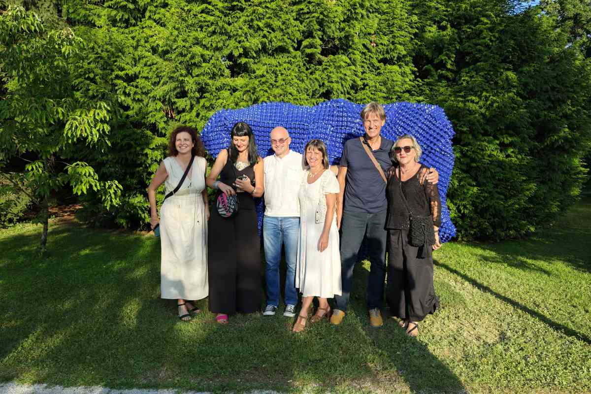 Umetniki in partnerji projekta ob skulpturi Fragment globine Skupina umetnikov in partnerjev projekta pozira pred modro skulpturo Fragment globine.