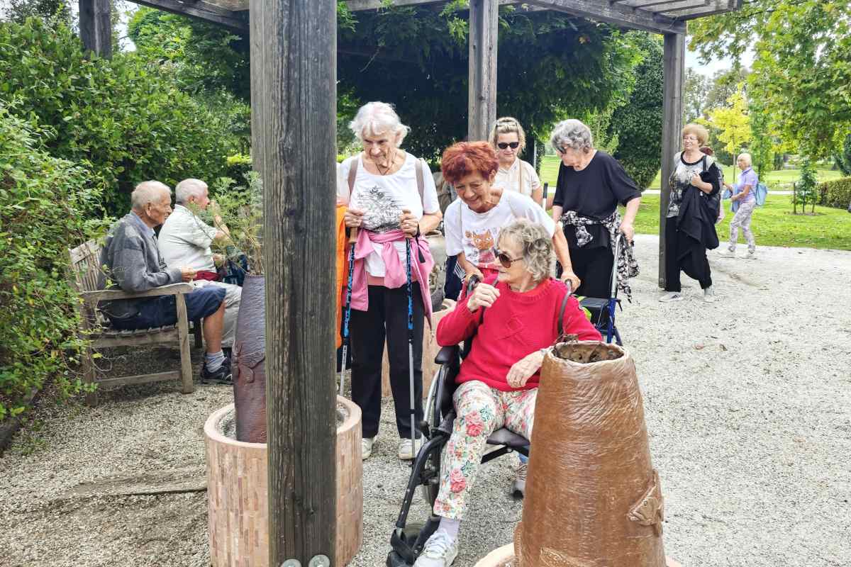Čutno doživljanje narave na Poti za spomin Obiskovalci Doma upokojencev Kranj se ob lesenem nadstrešku ustavljajo pri posodah z naravnimi predmeti, ki jih lahko opazujejo in tipajo.