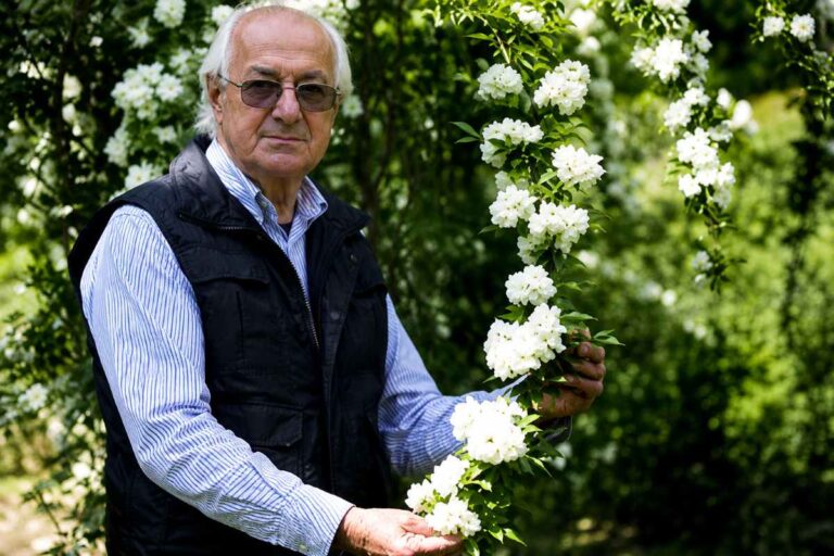 Portret Vladimirja Vremca sredi cvetočih grmov, ki držijo vejo.