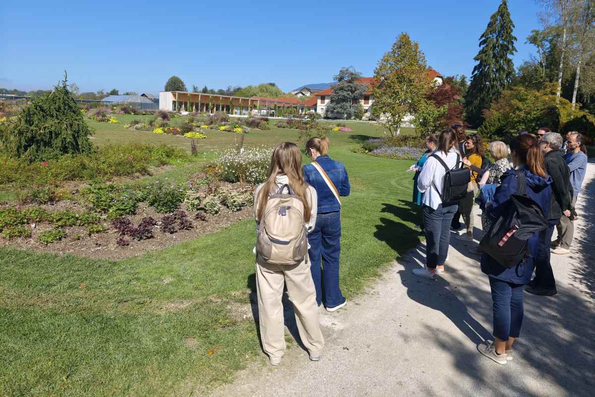 Strokovna izobraževanja: ogled zasaditev v Arboretumu Udeleženci na parkovni poti opazujejo gredice s trajnicami in grmovnicami, obdane s trato in drevesi.